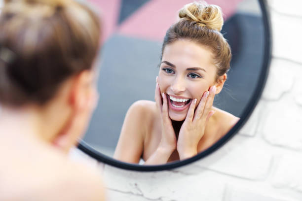 istock Young woman cleaning face in bathroom mirror 1066627086