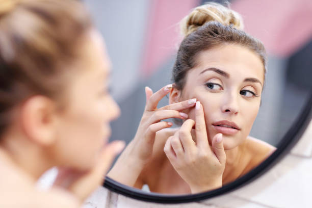 istock Young woman cleaning face in bathroom mirror 1066627162