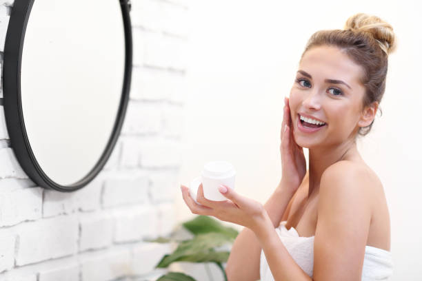 istock Young woman cleaning face in bathroom mirror 1066628378