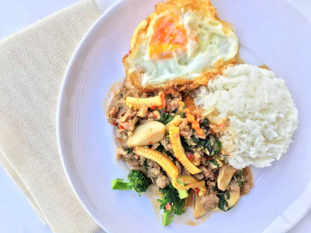 Photo of stir fried minced pork with basil eating with rice and fried egg on white background. Thai Food.