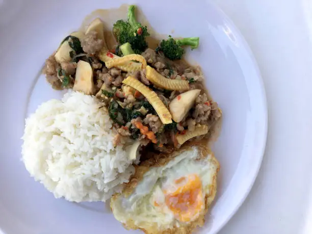 Photo of stir fried minced pork with basil eating with rice and fried egg on white background. Thai Food.
