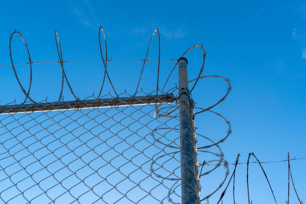 istock barbed wire fence on blue sky 1066641356