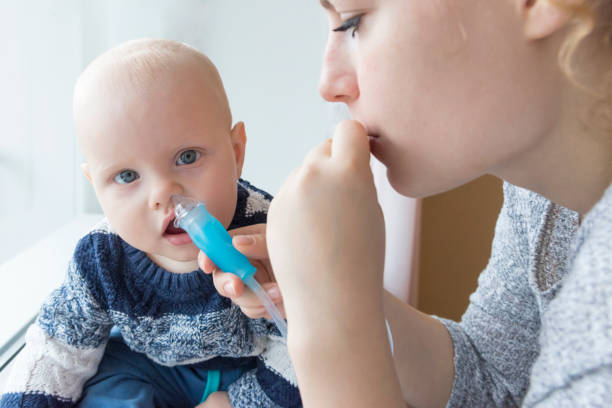 istock Mom cleans baby's nose using a nasal aspirator 1066647546