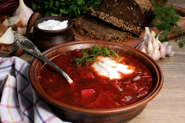Borscht-vegetable beetroot soup, on the table with slices of rye cereal bread and gluten of sour cream, garlic and herbs. Rustic style. stock photo