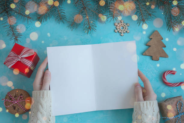 istock Female hands in a white sweater keep a Christmas card on a blue background 1066655716
