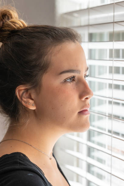 istock young woman looking through a window 1066657220