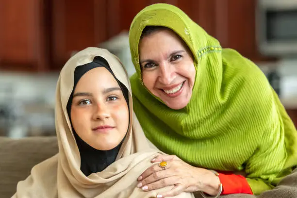Muslim mature woman posing with her young daughter looking at the camera