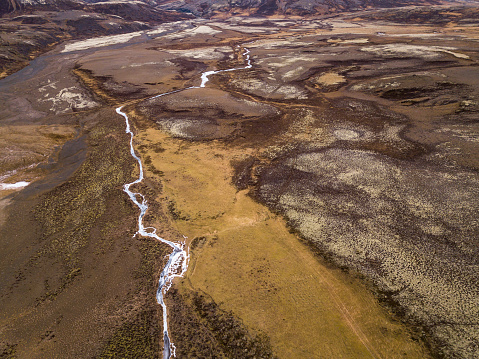 frozen river and dramatic dramatic volcanic landscape near laugarvatnshellir in iceland. captured by drone.