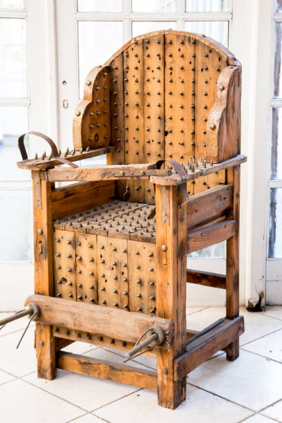 old wooden chair with spikes for torture stock photo