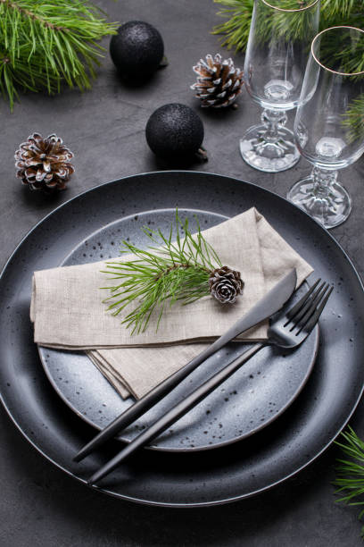 istock Dark christmas table setting design. Black  plates, champagne glasses, fork and knife set with napkin, fir branch, christmas decorations 1066663400