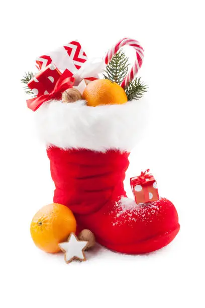 Santa boots with sweets and gifts on white background