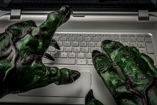 Acoso cibernético, fraude online, virus de computadora o internet trolls concepto con las manos de un troll que escribe en el teclado de un ordenador portátil photo