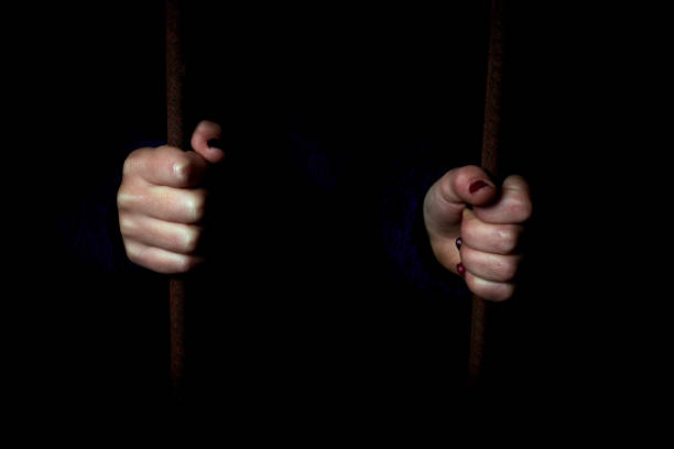 istock Child hands holding bars in a dark hiding place. 1066670198