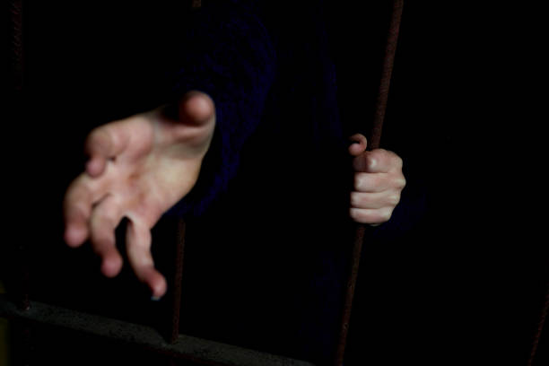 istock Child hands holding bars in a dark hiding place. 1066670378