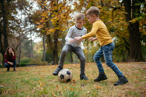 Family having football time outdoors. Shallow DOF. Developed from RAW; retouched with special care and attention; Small amount of grain added for best final impression. 16 bit Adobe RGB color profile.