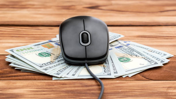 Computer mouse with money on the wooden table. stock photo