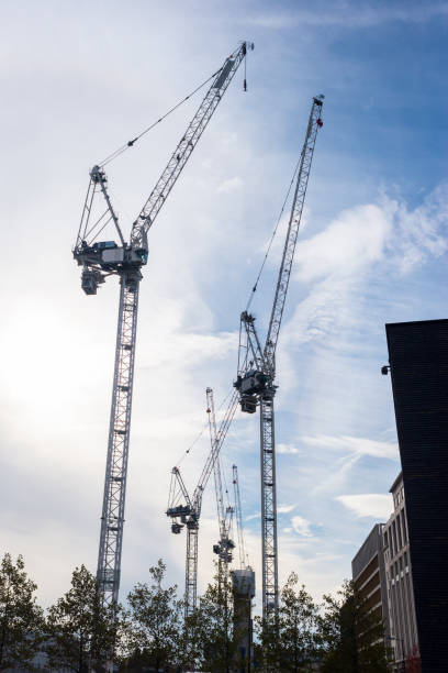 istock Silhouettes of several massive construction cranes with sky blue sky in the background 1066685786