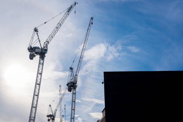 istock Silhouettes of three massive construction cranes with sky blue sky in the background 1066688050