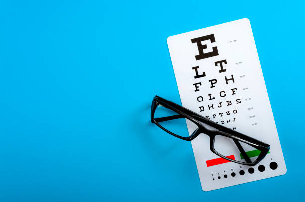 ojos sanos, examen oftalmológico y concepto de oftalmología con un par de gafas de visión y un gráfico de ojo aislado sobre fondo azul con copyspace - doctor reading chart human eye fotografías e imágenes de stock