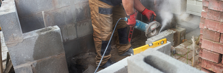 Building contractor cutting concrete block with an angle grinder on site