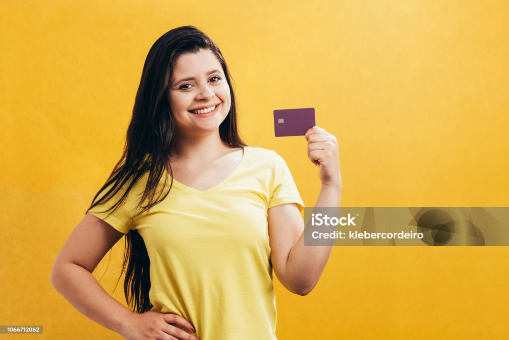 Ritratto di una ragazza felice che mostra carta di credito di plastica isolata su sfondo giallo - Foto stock royalty-free di Carta di Credito