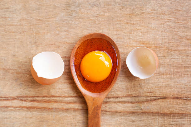 istock Egg yolk on wooden spoon, Wooden background. 1066724822