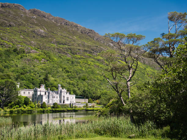 Kylemore Abbey in Ireland with reflection in water View of Kylemore Abbey in Ireland with reflection in the water and mountain in the background kylemore abbey stock pictures, royalty-free photos & images
