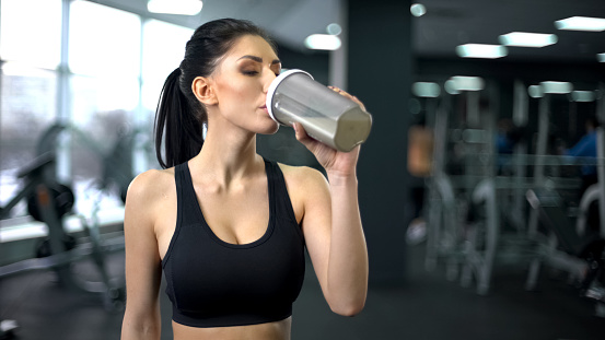 Deportiva mujer bebiendo el batido de proteína después del entrenamiento, nutrición de ganancia muscular, salud photo