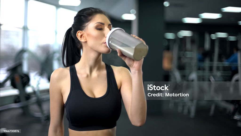 Desportiva mulher bebendo batido de proteínas após o treino, nutrição de ganho muscular, saúde - Foto de stock de Suplemento nutricional royalty-free