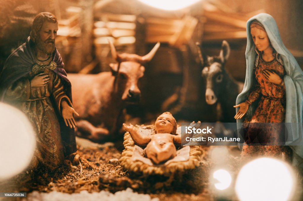 Antique Nativity Scene Lit With Christmas Lights An old Christmas nativity set, with Joseph, Mary, and the baby Christ child in a manger.  Animals and visitors also visible in the classic scene.  A warm holiday background. Nativity Scene Stock Photo