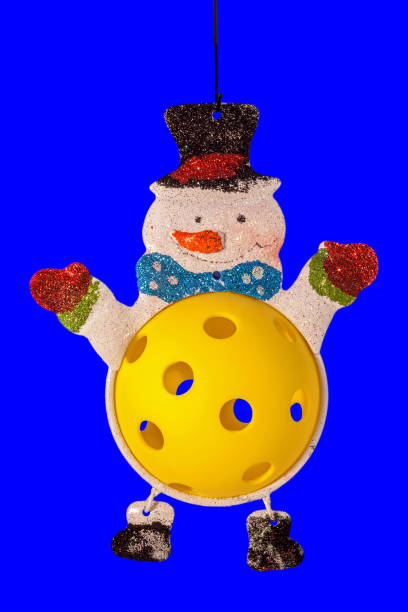 Pickleball ornament with a yellow pickleball snowman body on a blue background.