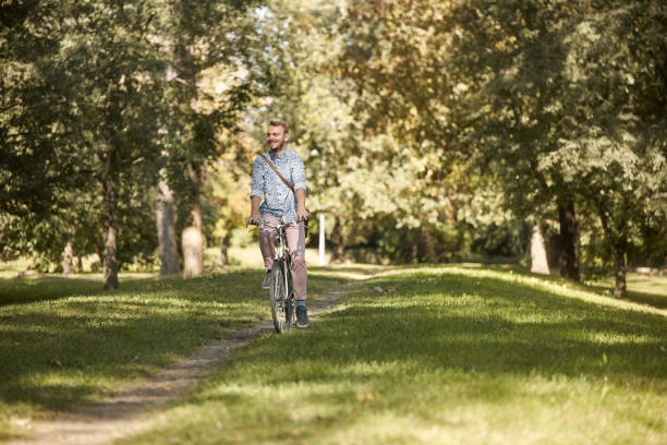 istock one young man, 20-29 years, riding bicycle in park trail outdoors. looking sideways, enjoying happy. 1066772540