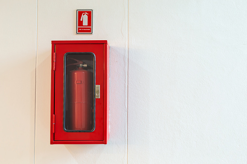 Fire extinguisher cabinet on white wall for building security, blank for copy space.