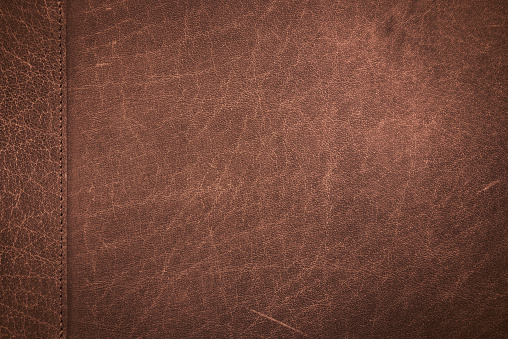 Close up classic brown scratched leather texture background with stitching patchwork. Genuine leather scratched texture