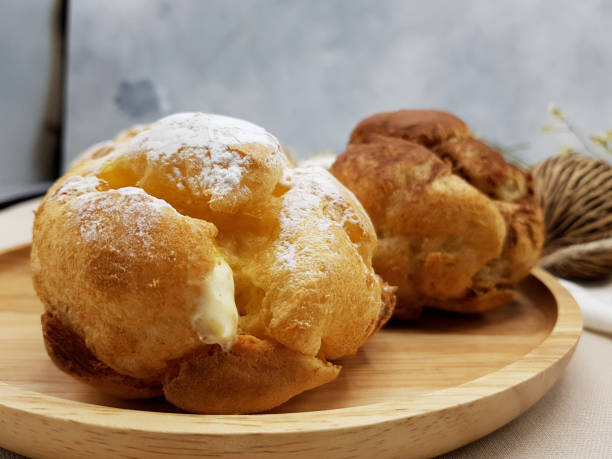 istock Chocolate and vanilla choux cream puff on wooden plate 1066814618