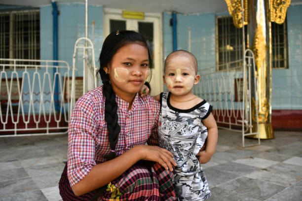 November 2018, Yangon. Myanmar. Burmese woman and child with Thanaka make-up Traditionally used in Myanmar by women, for over 2000 years, the paste is made from the ground bark of trees and is worn as make up and its properties include protection from sun burn. sule pagoda stock pictures, royalty-free photos & images
