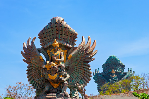 Landscape picture of old Garuda Wisnu Kencana GWK statues as  Bali landmark with blue sky as a background. Balinese traditional symbol of hindu religion. Popular travel destinations in Indonesia.