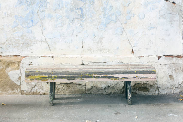 istock Weathered old aged wooden bench. Destroyed grunge blue plaster wall background. 1066820290