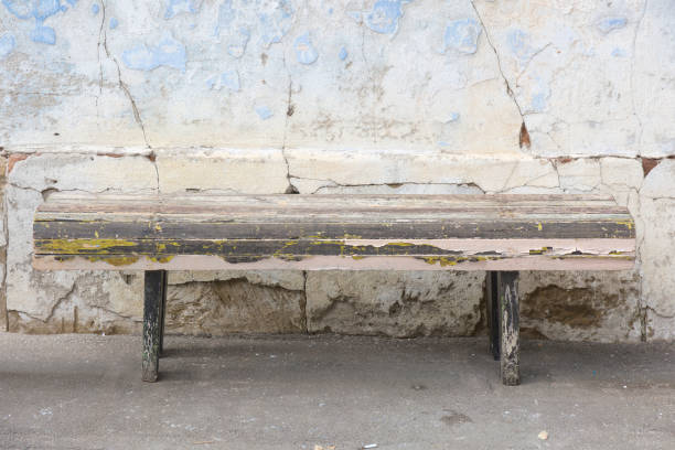 istock Weathered old aged wooden bench. Destroyed grunge blue plaster wall background. 1066820616