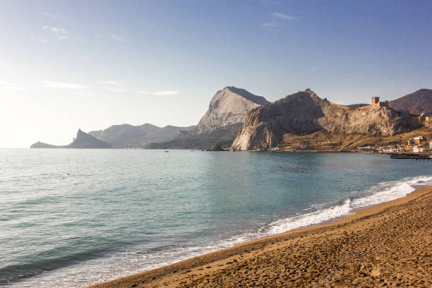 Sea coast and sandy beach with rocky mountains on a clear day