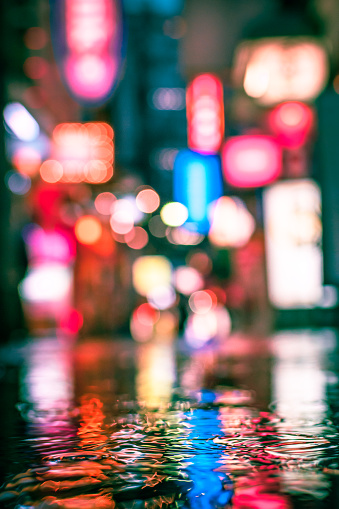 Close up of a puddle in the rain. Colorful background of blurred neon signs in Japan.