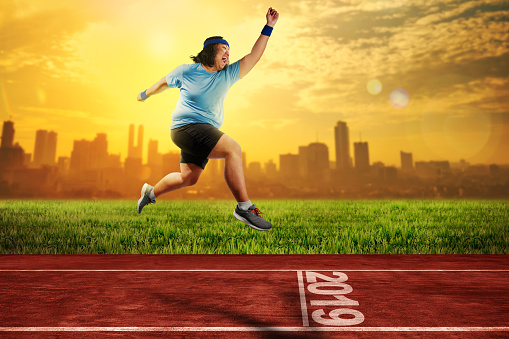 Attractive asian fat man running on running track with 2019 number on the start line. New Year Resolution 2019