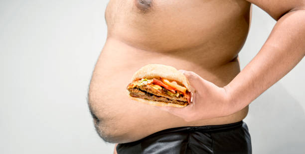 istock Man with overweight belly holding hamburger on his hand 1066834018