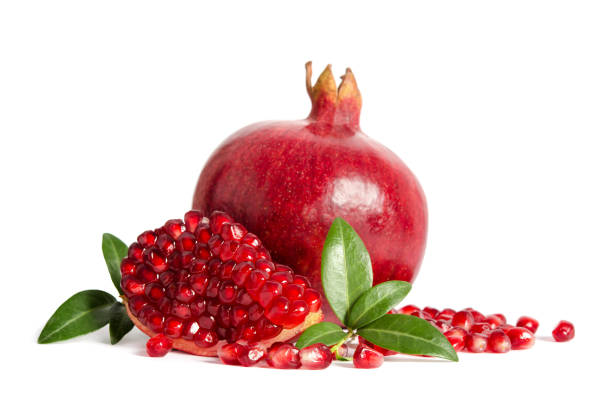 one whole and part of a pomegranate with pomegranate seeds and leaves isolated on white background stock photo