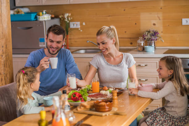istock Young happy parents sitting with their daughters at dining table and communicating. 1066842176