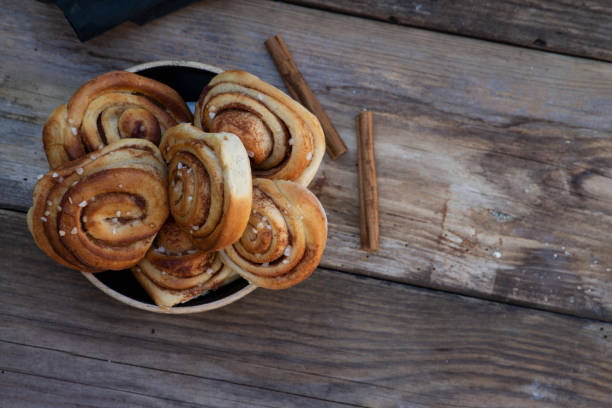 a bowl with cinnamon rolls on a wooden table stock photo