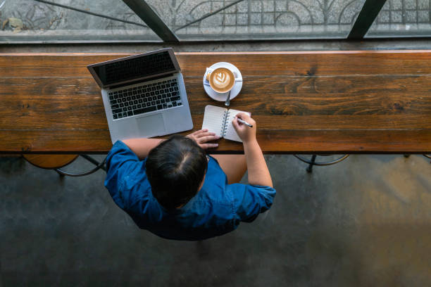istock High angle view of young woman writing notes 1066843236