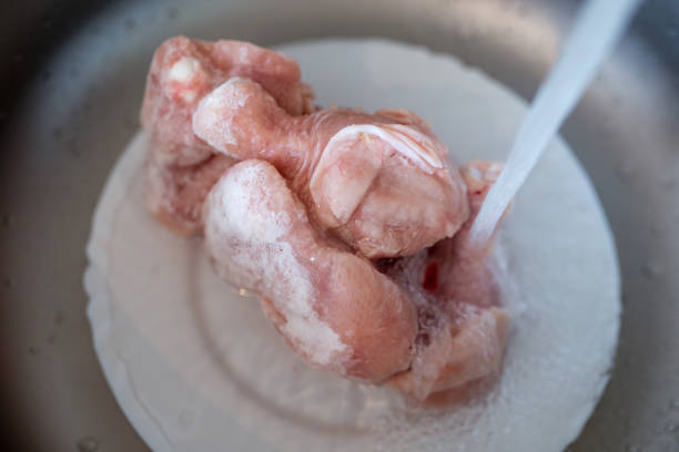 defrost the frozen chicken under the water - chicken food raw meat imagens e fotografias de stock