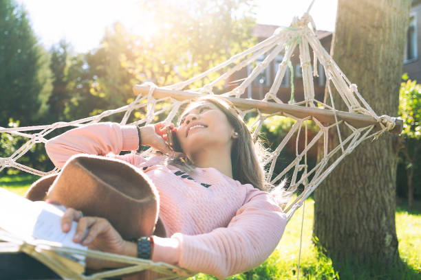 istock Young Asian woman talking on mobile phone and lying down on a hammock 1066852470