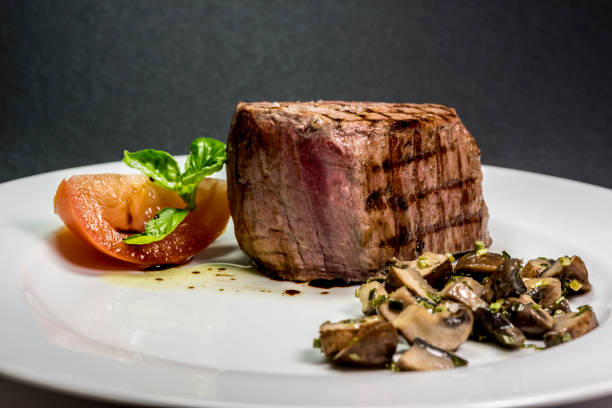 istock Roasted meat with tomatoes and mushrooms on a white plate 1066855270
